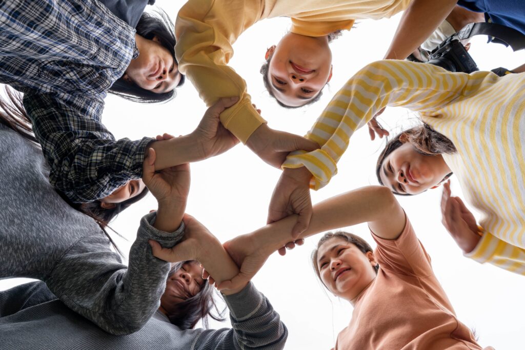 Participants link arms in a circle during a workplace mental health workshop in Singapore.